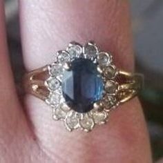 a close up of a person's hand wearing a ring with an oval blue stone