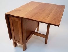 a wooden desk with two doors on the top and one drawer at the bottom, against a white background