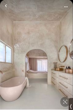 a bathroom with a tub, sink and large mirror in it's center area