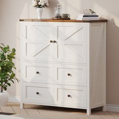 a white dresser with drawers and a potted plant in the corner next to it