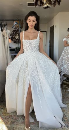 a woman in a white dress standing next to a chandelier