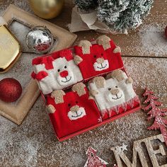 christmas decorations and ornaments are on the floor next to a red box with three small teddy bears