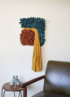 a brown chair sitting in front of a wall hanging