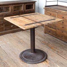 a wooden table sitting on top of a hard wood floor next to dressers and drawers