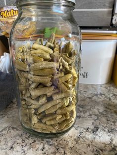 a glass jar filled with green beans on top of a counter