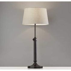 a lamp that is on top of a white table next to a gray wall and floor