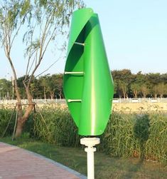 a green street sign sitting on the side of a road next to a lush green field