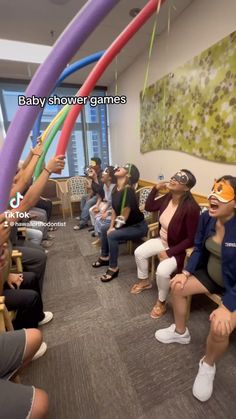 a group of people sitting in a room with some holding up large colorful streamers