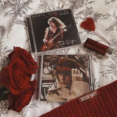 two cds and a red rose on a bed