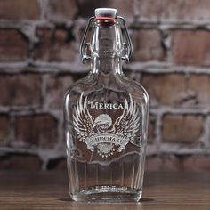 an empty liquor bottle sitting on top of a wooden table next to a brick wall