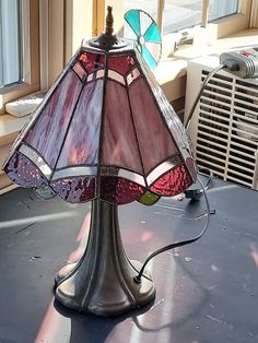 a lamp sitting on top of a table next to a window