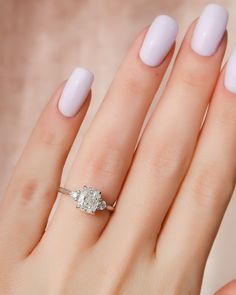 a woman's hand with a ring on it and a white manicured nail