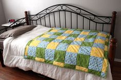 a bed with a green and yellow quilt on it