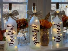 four bottles with lights on them sitting on a window sill