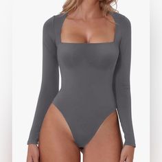 a woman wearing a bodysuit with long sleeves and no panties on the bottom is standing in front of a white background