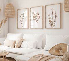 a living room filled with white furniture and pictures hanging on the wall above couches