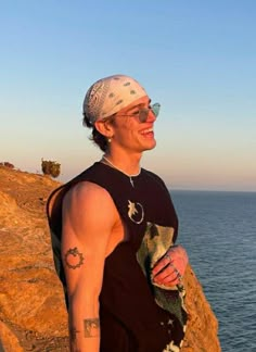 a man standing on top of a cliff next to the ocean