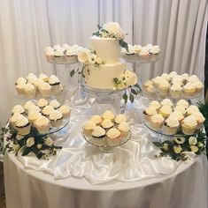 a table topped with lots of cupcakes covered in white frosting and flowers