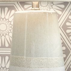 a lamp that is sitting next to a wall with a flower pattern on the side