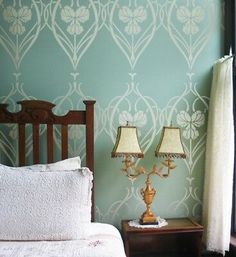 two lamps are sitting on a nightstand in front of a wallpapered room with a bed