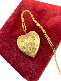 Description: Adorable and classic vintage 14k gold filled heart shaped locket on a gold filled chain. The lovely and feminine locket pendant has a pair of pink etched hearts on the front with some green etched leaves below them.  The interior of the locket is completely empty and can hold two photos (one on each side).  The back of this little locket has a shiny finish.  It closes securely with a snap.   Note there is some wear to the green on the leaves - see photos for details. The locket is attached to a new 20" long gold filled chain which secures with a lobster clasp. Beautiful piece of vintage jewelry. Measures:  Chain: 20'' long. Locket (with bail): 1 1/4'' long  and 1 1/8" long without the bail. The locket is about 1'' in wide. Weighs:   7.1 grams (locket with chain) Condition: In Heart Shaped Locket, Heart Locket Necklace, Photo Charms, Heart Locket, Locket Necklace, Gold Filled Chain, Classic Vintage, Vintage Gifts, Charm Jewelry