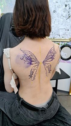 the back of a woman's body with purple and yellow tattoos on her back