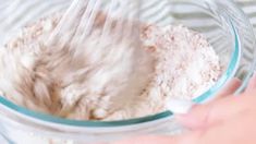 someone mixing ingredients in a glass bowl with a whisk