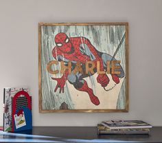 a spiderman poster hanging on the wall next to a book shelf with books and magazines