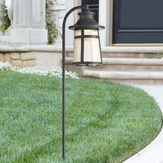 a lamp post in front of a house with grass and steps leading to the door