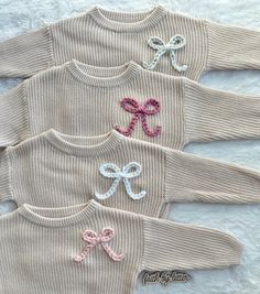 three knit sweaters with bows on them