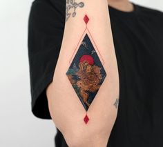 a woman with a tattoo on her arm holding up a red diamond and black diamond