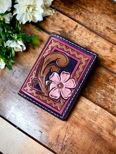 a wallet sitting on top of a wooden table next to flowers