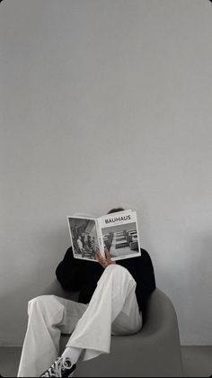 a person sitting in a chair reading a magazine