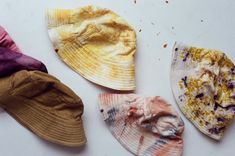 four hats are laid out on a white surface and one is yellow, the other has purple