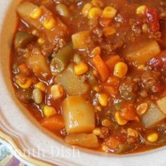 a bowl filled with chili and potatoes on top of a tablecloth covered table cloth