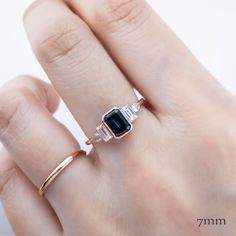 a woman's hand wearing a ring with an emerald and diamond set in it