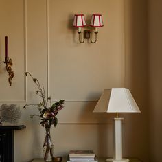 a table with a lamp and some books on it next to a wall mounted clock