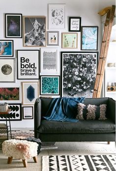 a black couch sitting in front of a wall covered in pictures