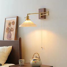 a lamp that is on the side of a bed next to a table with a basket