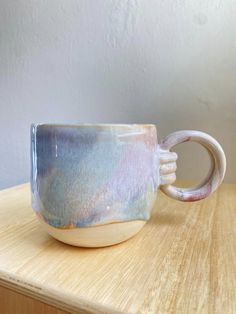 a coffee cup sitting on top of a wooden table next to a white and blue wall