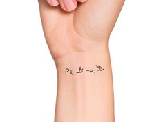 a woman's wrist tattoo with birds on it