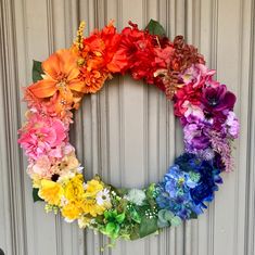 a colorful wreath made out of flowers on a door frame with the colors of the rainbow