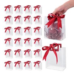 a hand is holding a clear bag with red ribbon around it and twelve small white boxes in the background