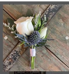 a boutonniere with white roses and greenery on an old wooden background