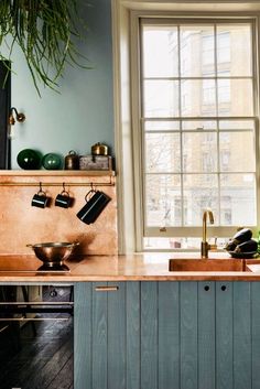 a kitchen with an oven, sink and window in the room that has blue walls