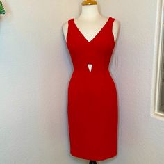 a red dress on a mannequin next to a white wall and potted plant