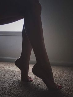 a woman's legs and feet are shown in the dark, with light coming through