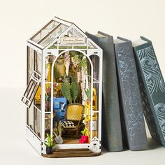 a miniature house sitting next to two books