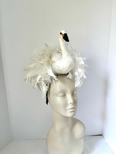 Bird Fascinator- Feather Headband- Swan Lake-   Derby- White Feather Headband- Diner in Blanc Hello,            This fascinator is perfect to add whimsical fun to any occasion. You'll be the life of the party with this great conversation piece Comes in 2 sizes. This MEDIUM SWAN feather fascinator has a white swan that is about 7" high with a puff of coque feathers.  It has great movement. It's not a real bird, it's Styrofoam covered with feathers and is very light. The coque feathers are about 6-8", placed on a straw circle and then placed on a 1/8" satin headband. The covered headband is stainless steel and is adjustable to fit any head size. I call her Princess Odette. -------------------------------- LARGE SIZE in press : https://etsy.me/3RZEslT   --------------------------------------- Whimsical Fitted Costume Headpiece For Races, Fitted Whimsical Costume Hat For Races, Fitted Whimsical Hat For Races, Feathered Headbands, Bird Fascinator, Princess Odette, Swan Costume, Yellow Fascinator, White Fascinator