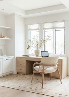 a chair sitting in front of a desk with a laptop on top of it next to a window